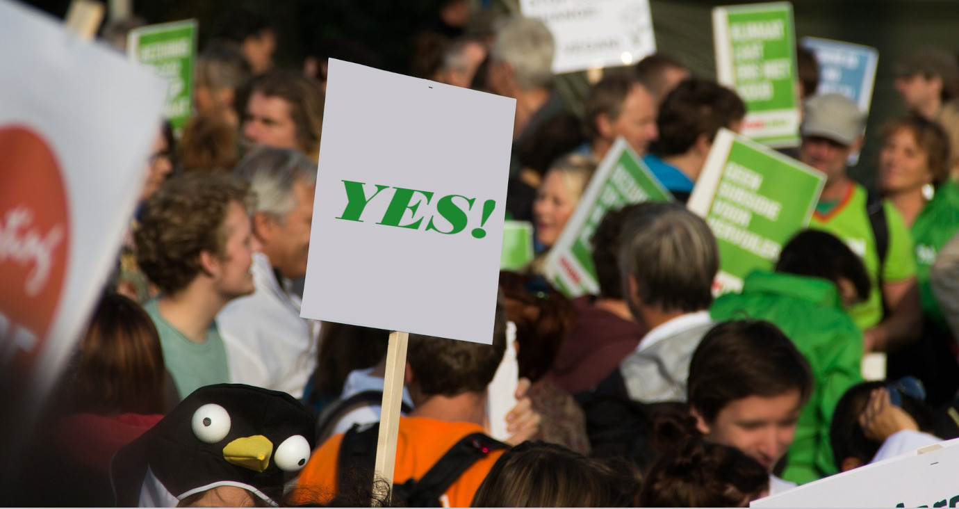 Demonstrierende Menschen und hochgehaltenes Plakat mit Aufschrift Yes!